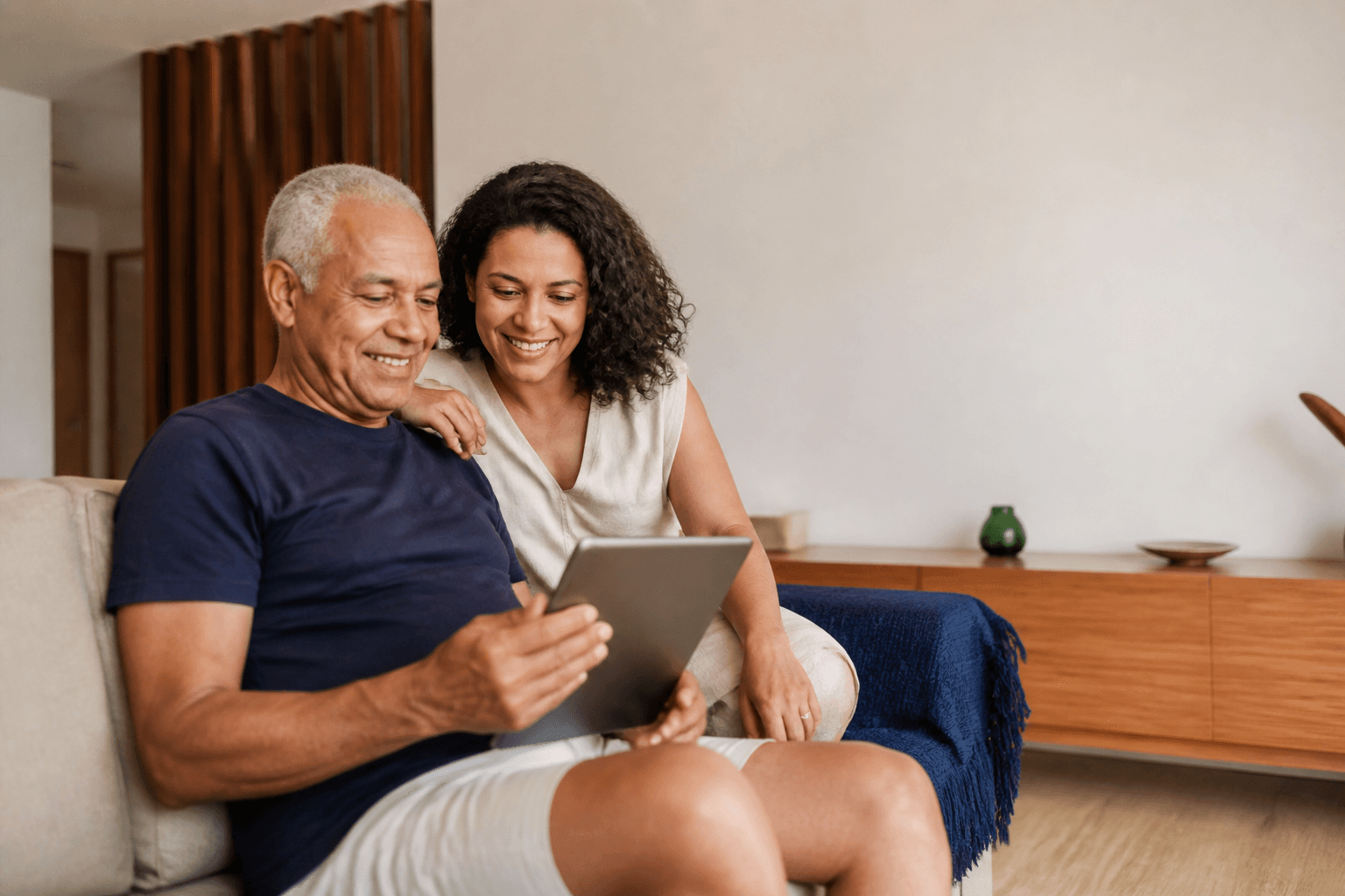 Homem mais velho e sua filha usando um tablet juntos
